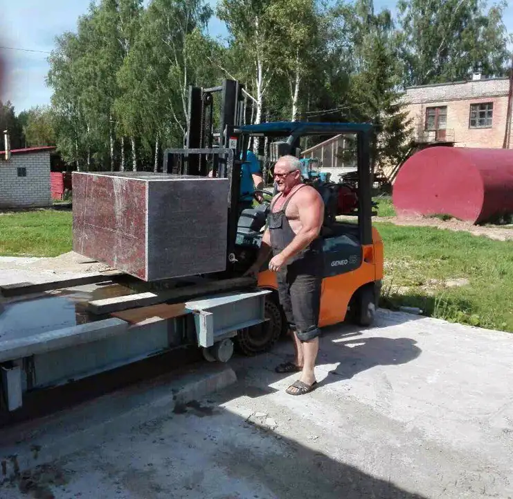 Мастер ПостКамень у погрузчика с блоком красного гранита для основания памятника Мулявину