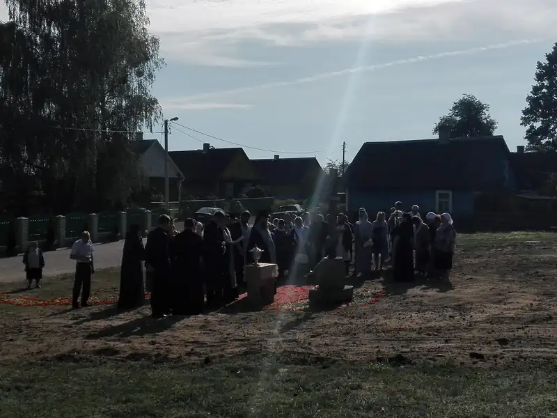 Освящение поклонного креста: священники и прихожане у креста, кадр пересекает луч солнечного света