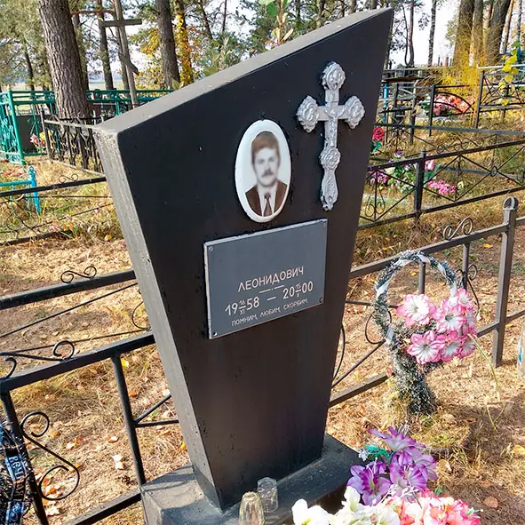 Металлический памятник, окрашенный в чёрный цвет, с овальным портретом, табличкой и накладным крестом